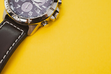 Wall Mural - Closeup shot of a black classic wrist watch isolated on a yellow background