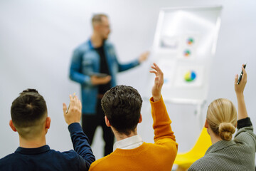 Group of young people sitting at a conference together raised hands to express their views. Business group meeting seminar training concept. Planning, analysis, collaborate work in teamwork.