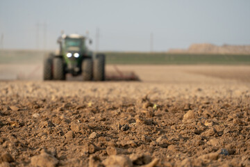 agricultural machinery works in the field. A tractor with a plow cultivates the land before sowing wheat and other cereals. Soft focus, plowed ground close-up. Empty space for inserting text