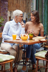 Wall Mural - An older woman having a friendly talk in the bar with her young female friend. Leisure, bar, friendship, outdoor