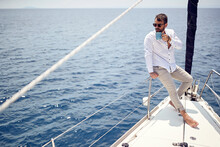 A Young Handsome Barefoot Male Model Is Enjoying The View At A Photo Shooting On A Yacht On The Seaside. Summer, Sea, Vacation