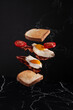 Toast with omelette and tomatoes in the air on a black background