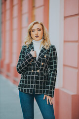 Poster - Caucasian female wearing a white turtleneck shirt and a black jacket posing for a fashion photoshoot