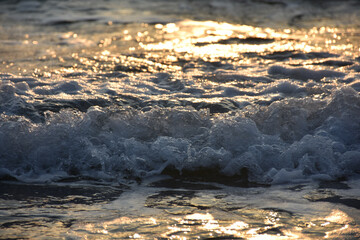 white and blue foam waves in the wild sea at sunset. Sea waves crushing on shore. White sea foam. white foam waves in the wild sea