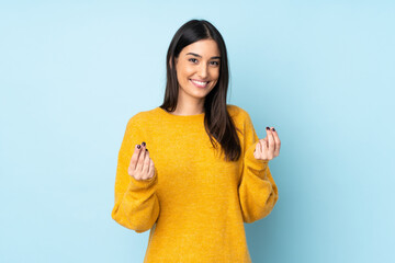 young caucasian woman isolated on blue background making money gesture