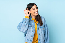 Young Caucasian Woman Isolated On Blue Background Listening To Something By Putting Hand On The Ear