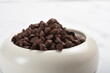 close up chocolate morsels or choco chips in bowl isolated white background.from top view