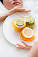 Wall Mural - partial view of woman holding plate with citrus slices while taking milk bath.