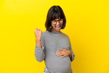 Wall Mural - Young pregnant woman over isolated yellow background celebrating a victory