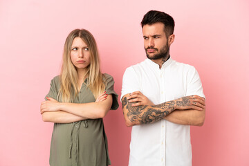 Wall Mural - Pregnant woman and man over isolated pink background annoyed angry in furious gesture