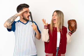 Couple playing baseball over isolated white background with surprise and shocked facial expression