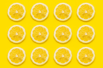 Wall Mural - background of ripe lemon slices against on a yellow background. Top view, flat lay