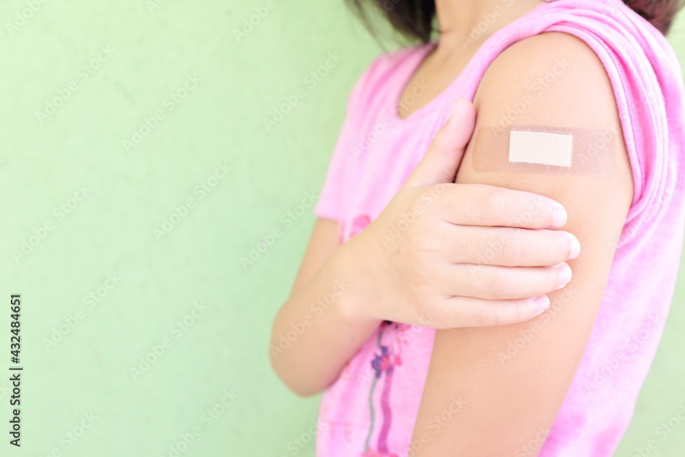 Closeup of shoulder of a vaccinated young Asian girl with adhesive bandage in thumbs up. Young people, children and kids vaccination for covid-19 vaccine. - obrazy, fototapety, plakaty 