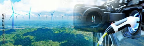 Charge EV car vehicle electric battery on station with wind turbine blue sky on panoramic background. Idea nature electric energy technology green eco car environment friendly concept. Double exposure