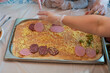 Cooking pizza, children's hands in gloves for cooking, lay out ingredients