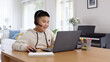 © ChayTee - Young asia boy student wear headset headphone with computer laptop videocall talk present online e-learning class study with teacher, social distance learn language at home, homeschooling concept.