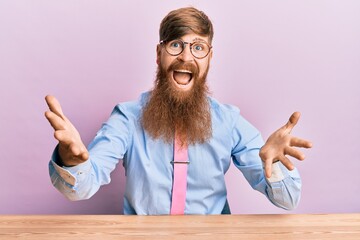 Poster - Young irish redhead man wearing business shirt and tie sitting on the table smiling cheerful offering hands giving assistance and acceptance.