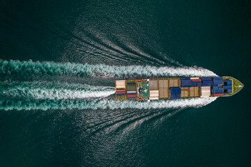 Aerial top view of cargo ship with contrail in the ocean sea ship carrying container and running for export from container international port to custom ocean concept freight shipping by ship service