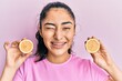 © Krakenimages.com - Hispanic teenager girl with dental braces holding lemon winking looking at the camera with sexy expression, cheerful and happy face.