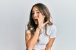 © Krakenimages.com - Young brunette woman wearing casual white t shirt hand on mouth telling secret rumor, whispering malicious talk conversation