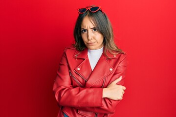 Poster - Young brunette woman wearing red leather jacket skeptic and nervous, disapproving expression on face with crossed arms. negative person.