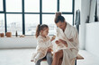 © gstockstudio - Mother and daughter in bathrobes smiling and cleaning teeth