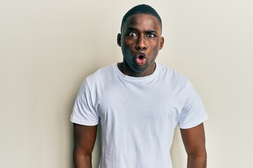 Young african american man wearing casual white t shirt scared and amazed with open mouth for surprise, disbelief face