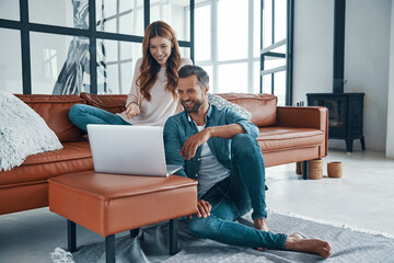 Sticker - Beautiful young couple using laptop and smiling 