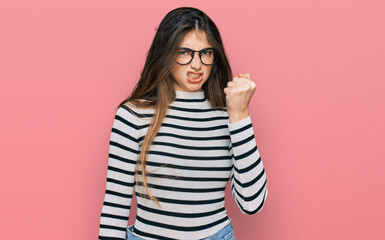 Sticker - Young beautiful teen girl wearing casual clothes and glasses angry and mad raising fist frustrated and furious while shouting with anger. rage and aggressive concept.