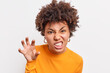 © wayhome.studio  - Afro American woman makes grimace scary face holds hand as if claw clenches teeth wants to scare child tells horror story wears casual clothes isolated over white studio background growls like animal