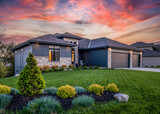 Fototapeta  - Luxury home during twilight golden hour with pink and purple sky and lush landscaping in Nebraska USA