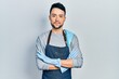 © Krakenimages.com - Young hispanic man wearing apron with arms crossed relaxed with serious expression on face. simple and natural looking at the camera.