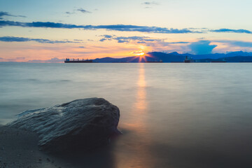 Wall Mural - Sunset or sunrise seascape from rocky shore at Kitsilano Beach on an idyllic summer evening in Vancouver, B.C., Canada.