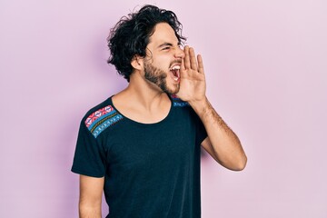 Poster - Handsome hispanic man wearing casual t shirt shouting and screaming loud to side with hand on mouth. communication concept.