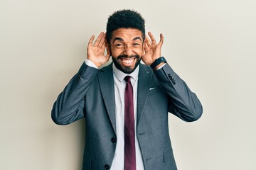 Canvas Print - Handsome hispanic man with beard wearing business suit and tie trying to hear both hands on ear gesture, curious for gossip. hearing problem, deaf