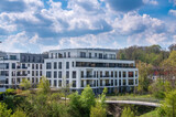Fototapeta Londyn - Modern apartment buildings with green in the foreground and cloudy spring sky in the background