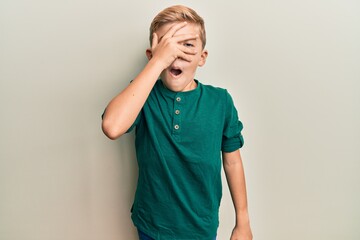 Wall Mural - Little caucasian boy kid wearing casual clothes peeking in shock covering face and eyes with hand, looking through fingers afraid