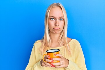 Sticker - Young blonde girl holding coffee depressed and worry for distress, crying angry and afraid. sad expression.