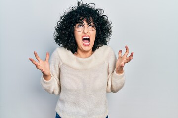 Sticker - Young middle east woman wearing casual white tshirt crazy and mad shouting and yelling with aggressive expression and arms raised. frustration concept.