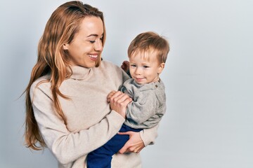 Young caucasian woman holding and hugging her son with love. Family of two bonding together. Mother holding infant toddler