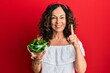 © Krakenimages.com - Middle age hispanic woman holding bowl with green peppers smiling with an idea or question pointing finger with happy face, number one