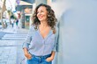 © Krakenimages.com - Middle age hispanic woman smiling happy leaning on the wall at the city.