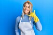 © Krakenimages.com - Beautiful blonde woman wearing cleaner apron and gloves smiling doing phone gesture with hand and fingers like talking on the telephone. communicating concepts.