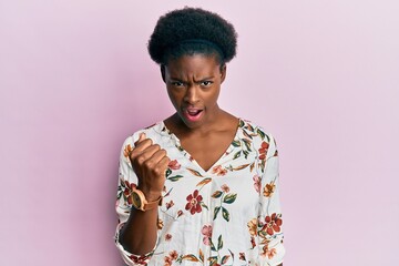 Sticker - Young african american girl wearing casual clothes angry and mad raising fist frustrated and furious while shouting with anger. rage and aggressive concept.