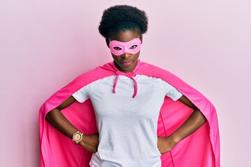 Poster - Young african american girl wearing super hero costume and medical mask skeptic and nervous, frowning upset because of problem. negative person.