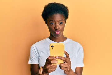 Poster - Young african american girl using smartphone and earphones looking at the camera blowing a kiss being lovely and sexy. love expression.