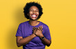 African american woman with afro hair wearing casual purple t shirt smiling with hands on chest with closed eyes and grateful gesture on face. health concept.