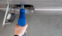 Closeup Hand Holding Blue Gas Pump Nozzle. Gas Station Worker Filling Up Bronze Pickup Truck Tank (Top View).