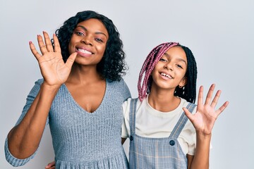 Poster - Beautiful african american mother and daughter wearing casual clothes and hugging waiving saying hello happy and smiling, friendly welcome gesture