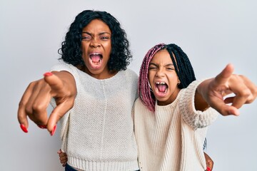 Wall Mural - Beautiful african american mother and daughter wearing casual clothes and hugging pointing displeased and frustrated to the camera, angry and furious with you